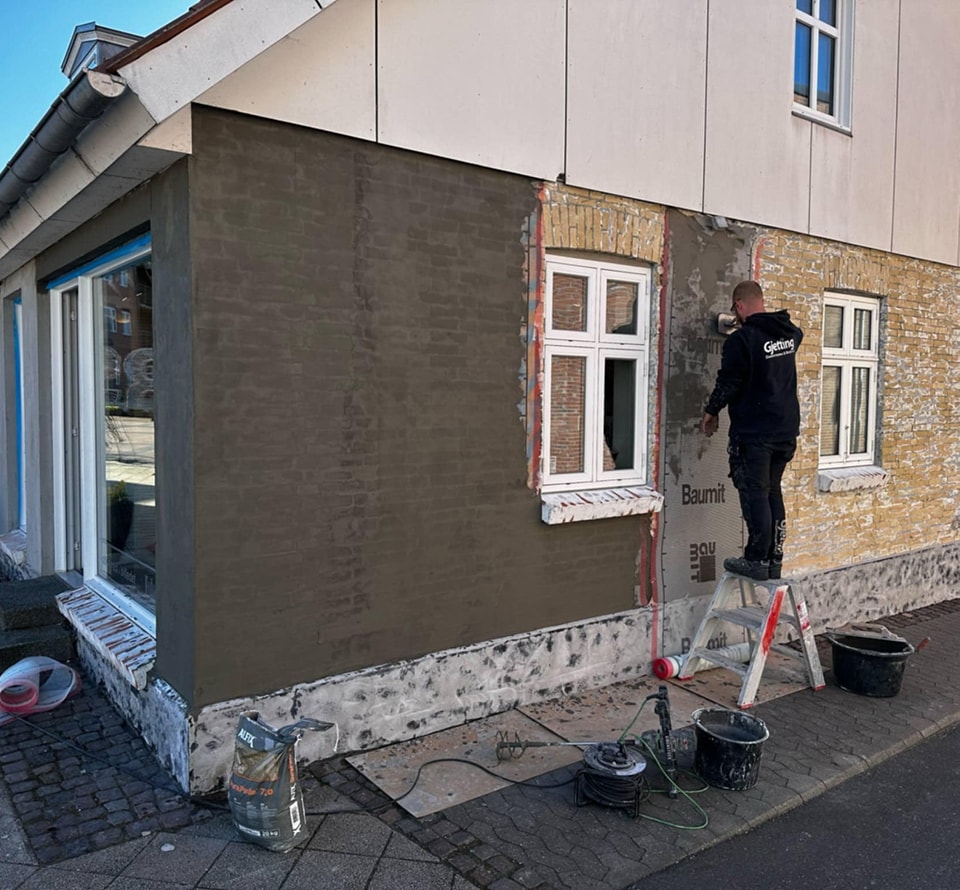 Håndværker pudser husfacade i byområde