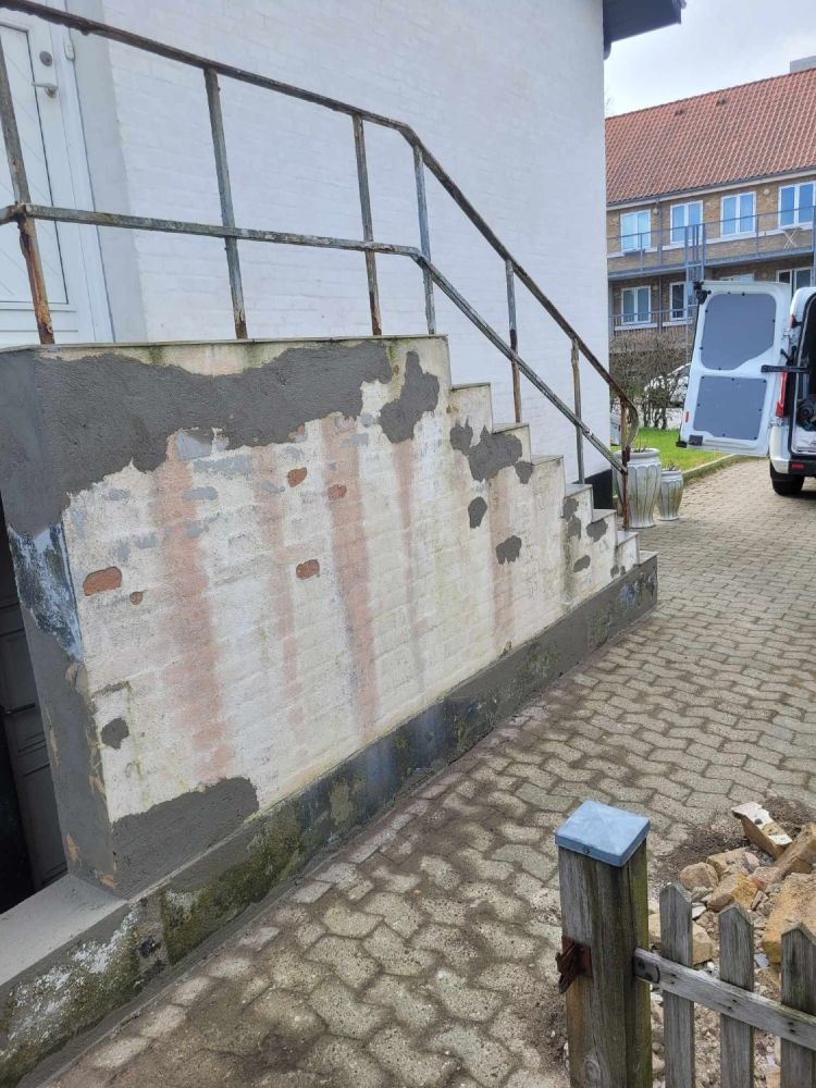 Slidt murtrappe med afskallet puds ved husindgang